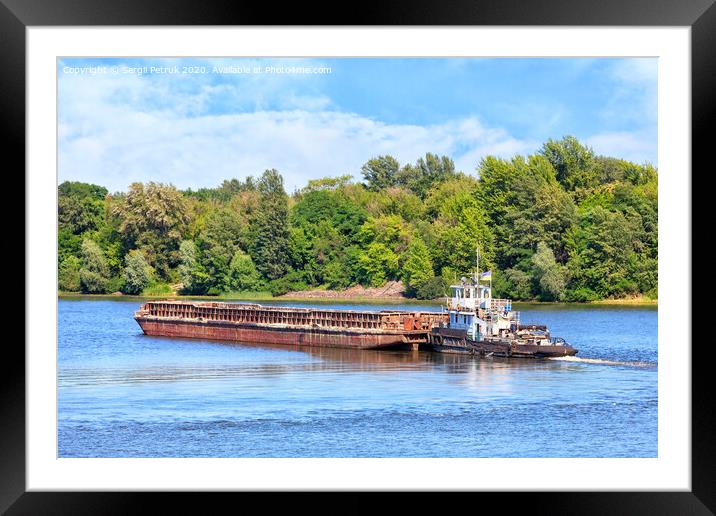 A river tug is pushing a rusty barge along the river along the shore. Framed Mounted Print by Sergii Petruk