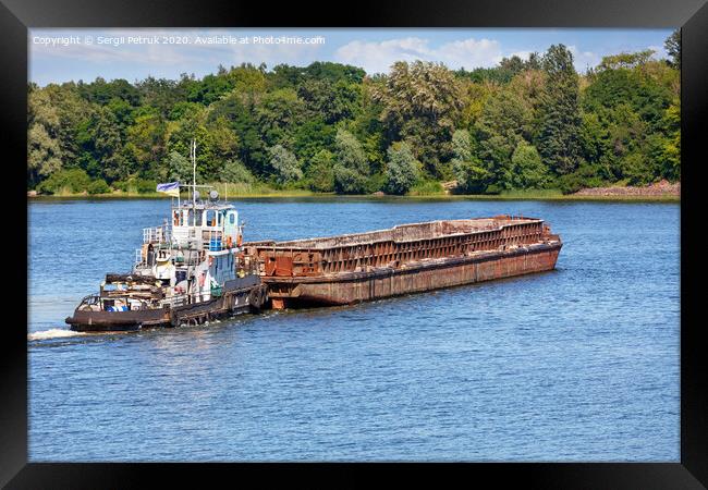 A river tugboat with an empty rusty barge goes crosses a wide river. Framed Print by Sergii Petruk