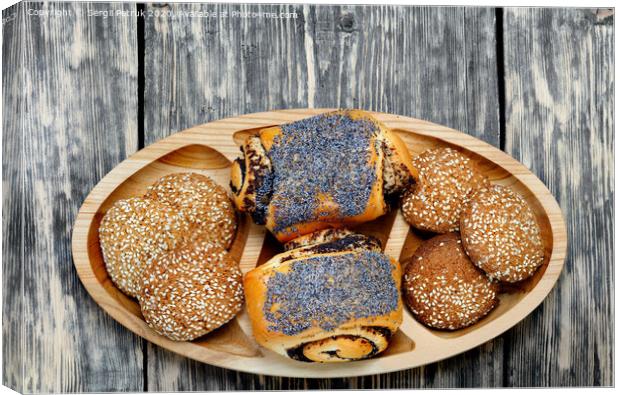 Homemade rolls with poppy seeds and oatmeal cookies with sesame seeds on a wooden tray, top view. Canvas Print by Sergii Petruk