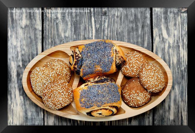 Homemade rolls with poppy seeds and oatmeal cookies with sesame seeds on a wooden tray, top view. Framed Print by Sergii Petruk