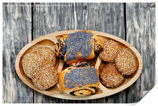 Homemade rolls with poppy seeds and oatmeal cookies with sesame seeds on a wooden tray, top view. Print by Sergii Petruk