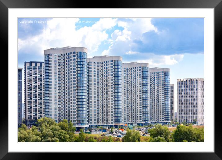 The facades of new residential high-rise buildings against a blue cloudy sky. Framed Mounted Print by Sergii Petruk