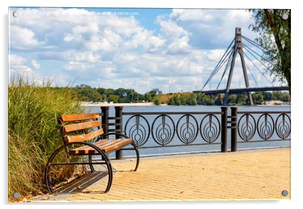 A wooden bench on the embankment of the Dnipro River against the background of yellow paving slabs and the northern bridge over the river in blur. Acrylic by Sergii Petruk