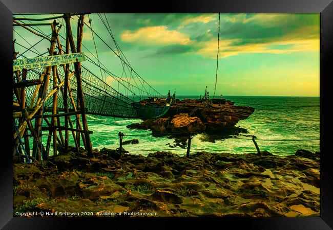 Challenge on a rope foot bridge to a rock island. Framed Print by Hanif Setiawan
