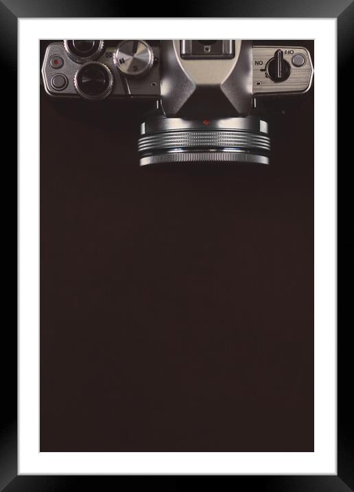 Dark brown background with digital camera, top view Framed Mounted Print by Tartalja 