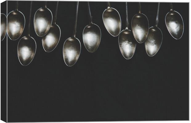 A row of silver tea spoons laying on canvas cloth, background Canvas Print by Tartalja 