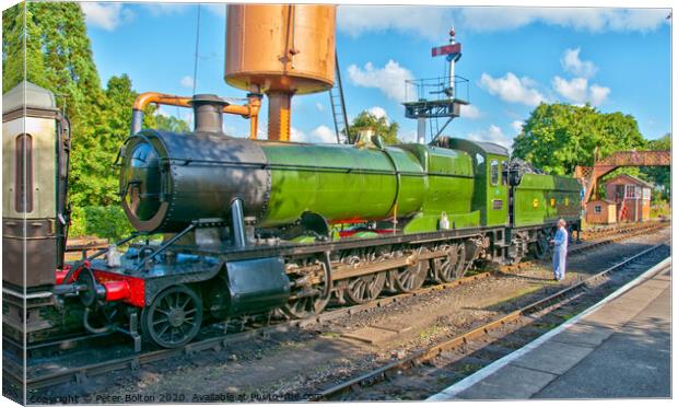 A steam locomotive takes on water at Buckfastleigh Station, Devon, UK. Canvas Print by Peter Bolton