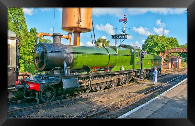 A steam locomotive takes on water at Buckfastleigh Station, Devon, UK. Framed Print by Peter Bolton