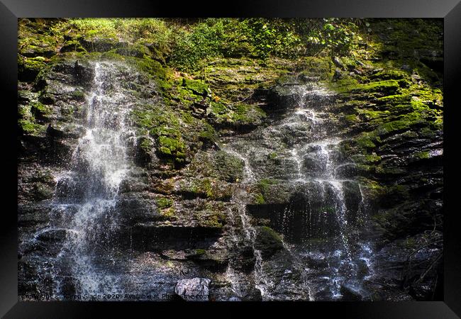 A double waterfall gently cascading over Ghanaian rocks and greenery Framed Print by Karen Slade