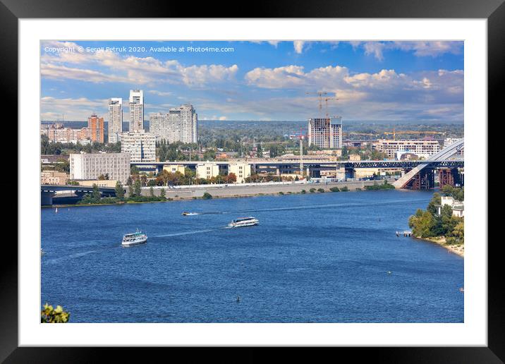 Pleasure boats run along the water surface of the Dnipro along the city embankment of Kyiv against the backdrop of a bright, beautiful sky and city buildings. Framed Mounted Print by Sergii Petruk