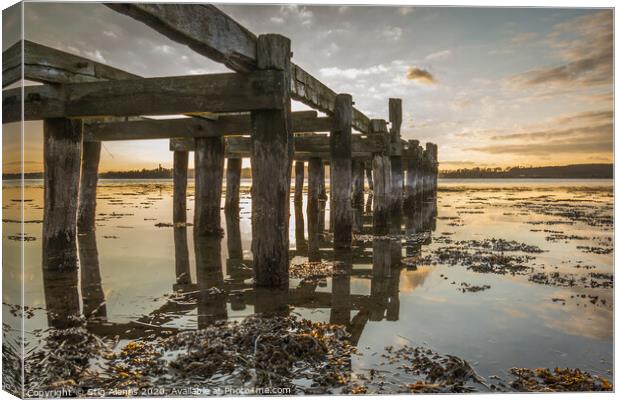 Old wooden jetty with poles reflecting in the water Canvas Print by Stig Alenäs