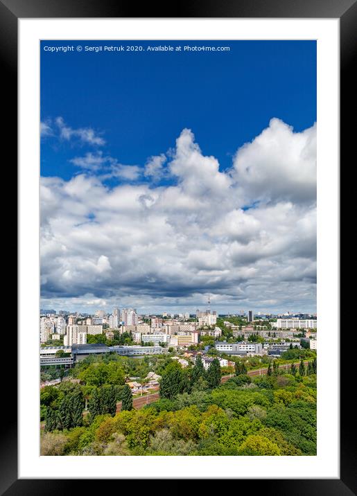 An urban landscape with a green park, residential areas and a TV tower against a bright blue sky with thickening clouds. Framed Mounted Print by Sergii Petruk