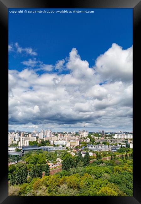 An urban landscape with a green park, residential areas and a TV tower against a bright blue sky with thickening clouds. Framed Print by Sergii Petruk
