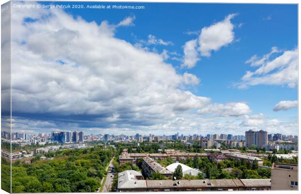 A cityscape with a green park in an old residential area of the city and new buildings on the horizon against a bright blue sky with thickening clouds. Canvas Print by Sergii Petruk