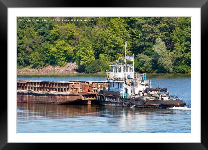 An old river tug pushes an empty barge ahead of itself along the river bank. Framed Mounted Print by Sergii Petruk