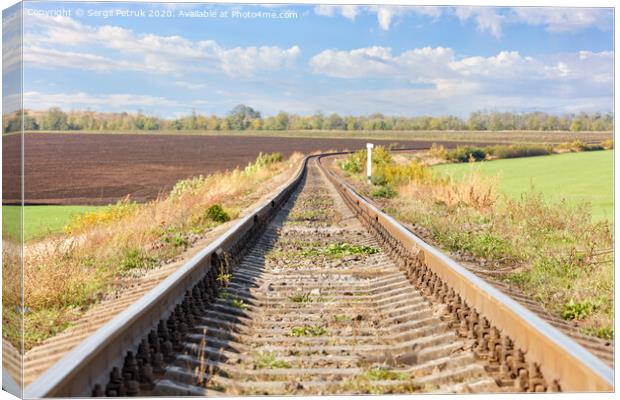 A single railroad track with a bend among the fields against the backdrop of a rural landscape. Canvas Print by Sergii Petruk