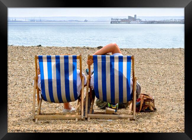 A couple on the beach in deckchairs silhouetted through the canvas at Southend on Sea, Essex, UK. Framed Print by Peter Bolton