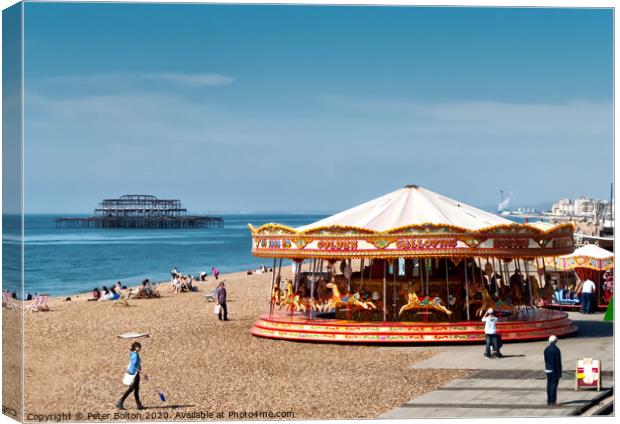 A merry-go-round on Brighton Beach on a summer day with West Pier ruins in the background. Sussex, UK. Canvas Print by Peter Bolton