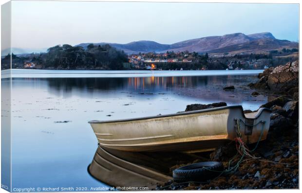 A dinghy moored at the loch's edge with reflected view of Portree  Canvas Print by Richard Smith
