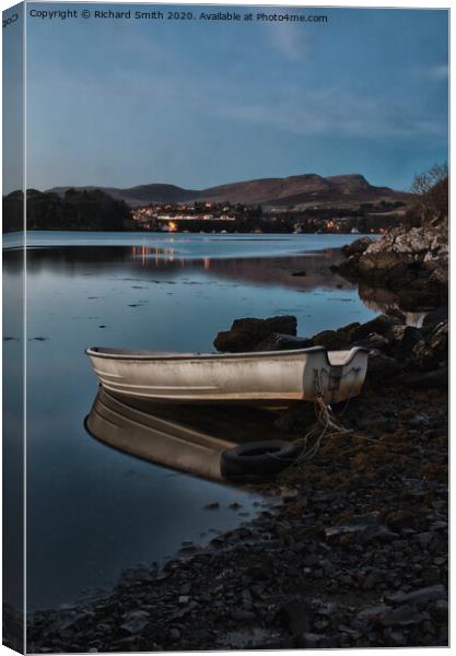 A dinghy moored on the shore of loch Portree reflected in the water  Canvas Print by Richard Smith