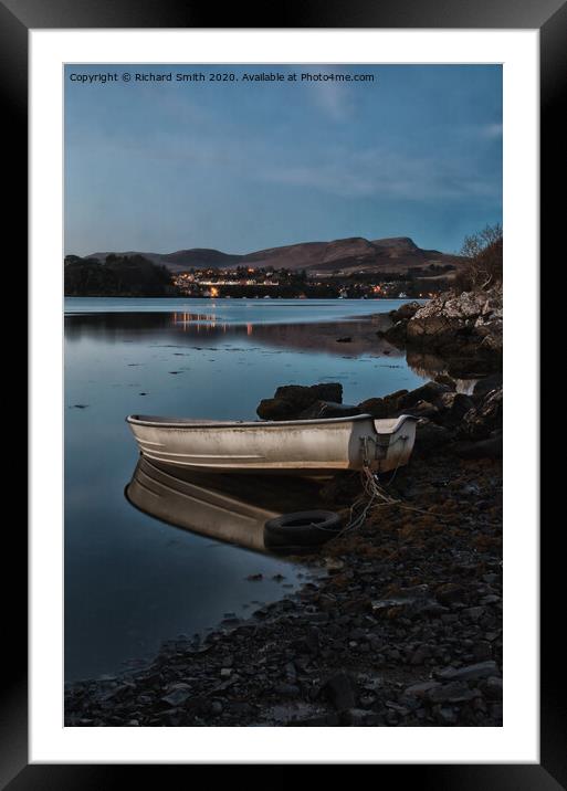 A dinghy moored on the shore of loch Portree reflected in the water  Framed Mounted Print by Richard Smith