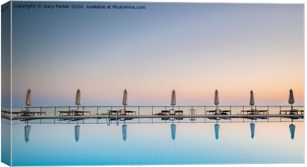 row of sunbeds and sun shades, reflecting in a still swimming pool, as the sun sets, in the Mediterranean	 Canvas Print by Gary Parker
