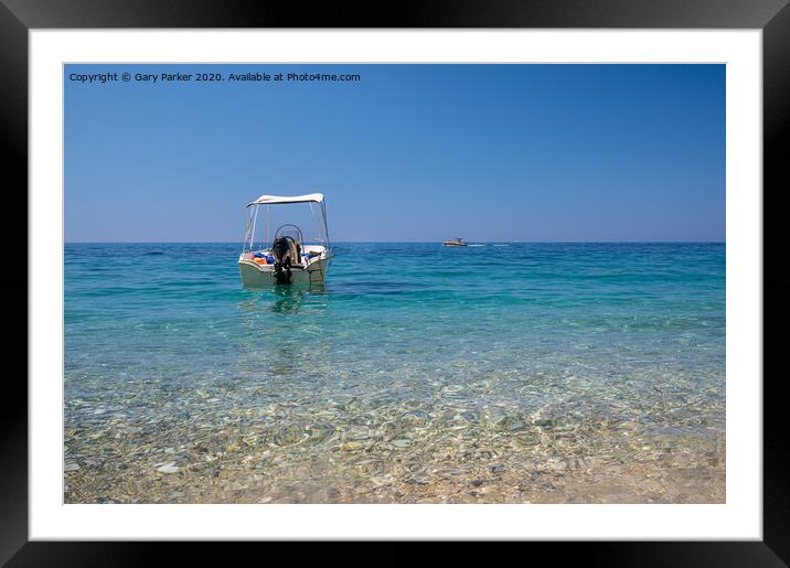 A small motorboat, floating in the crystal clear Mediterranean sea, off the coast of a Greek island Framed Mounted Print by Gary Parker