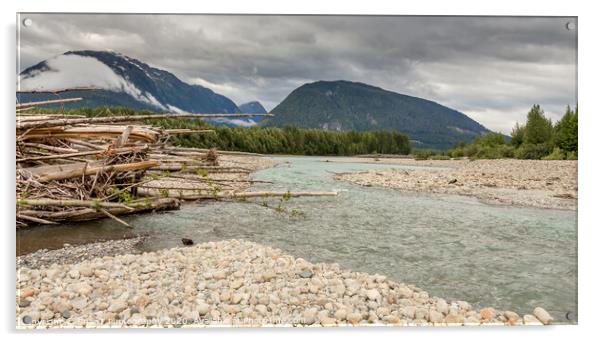 Log jam at the Shames and Skeena River confuence, on a cloudy day, with forest and mountains in the background. Acrylic by SnapT Photography