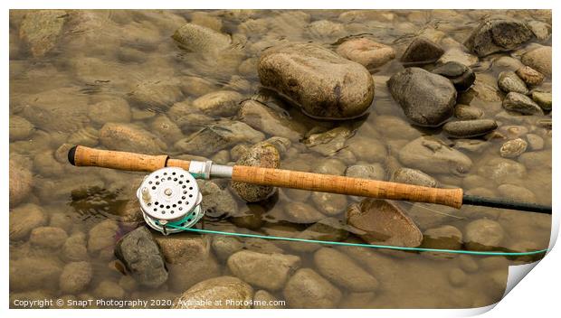 Spey fly rod and reel resting on wet rocks beside a river. Print by SnapT Photography