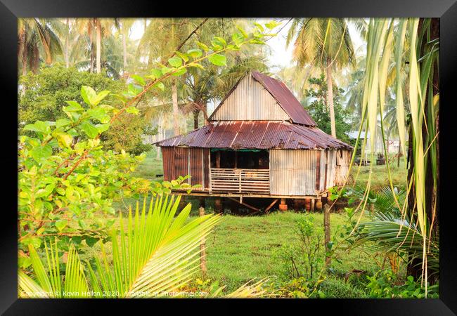 Small house surrounded by coconut palm trees Framed Print by Kevin Hellon