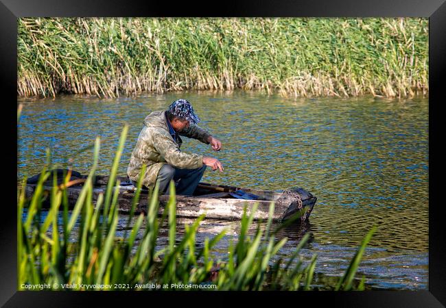 A fisherman in a wooden boat is fishing.  Framed Print by Vitalii Kryvolapov
