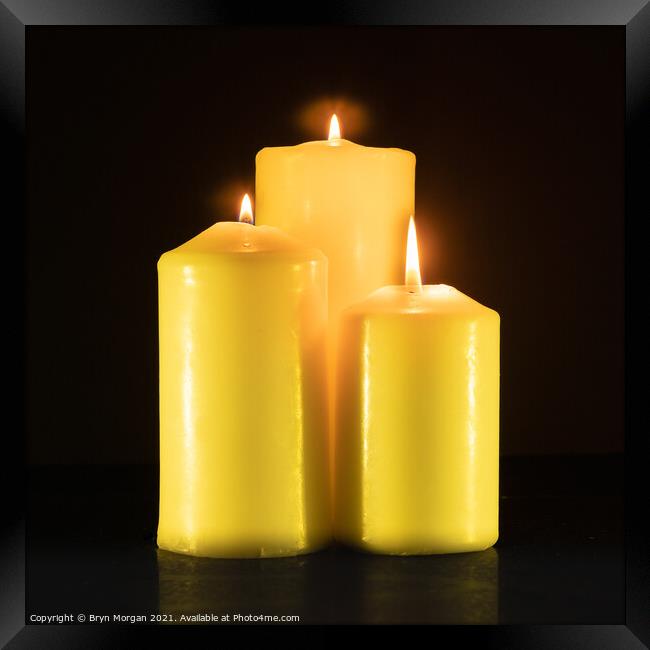 Three burning candles in the darkness Framed Print by Bryn Morgan