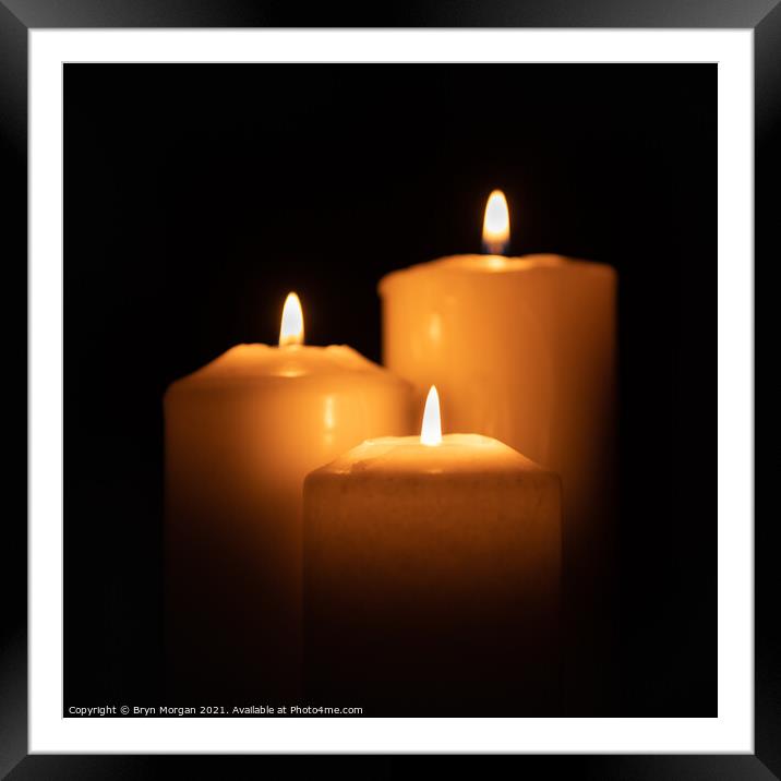 Three burning candles in the darkness Framed Mounted Print by Bryn Morgan