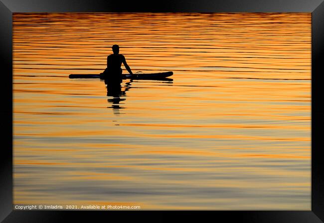 Silhouetted paddle boarder peaceful sunset Framed Print by Imladris 
