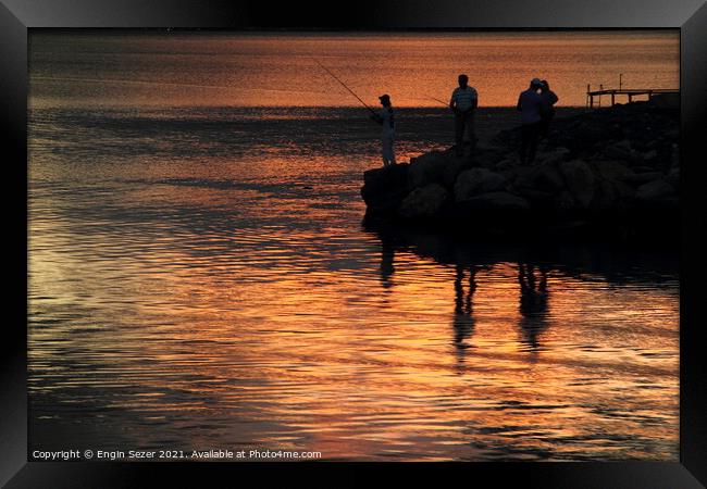 Silhouette of fishing people standing next to a bo Framed Print by Engin Sezer