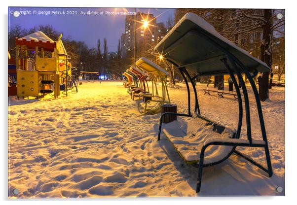 Wooden benches and a playground in the winter city evening park are covered with snow against the background of blue twilight. Acrylic by Sergii Petruk