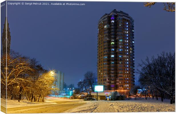 High-rise apartment building against the background of a city street in a winter city evening park covered with snow against a background of blue twilight. Canvas Print by Sergii Petruk