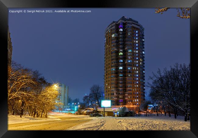 High-rise apartment building against the background of a city street in a winter city evening park covered with snow against a background of blue twilight. Framed Print by Sergii Petruk