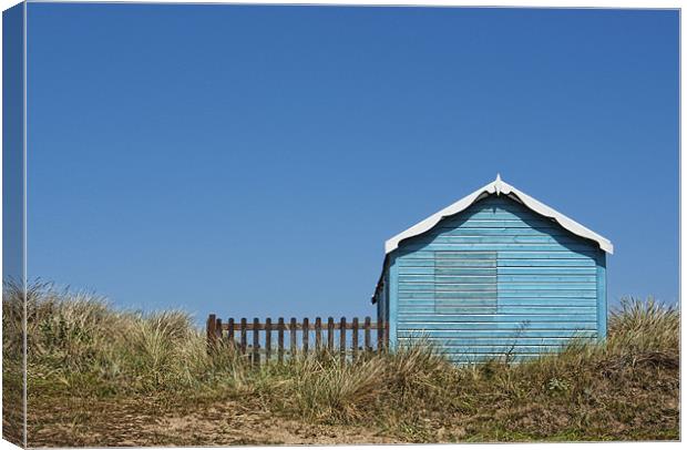 Blue beach hut on a hill Canvas Print by John Edwards