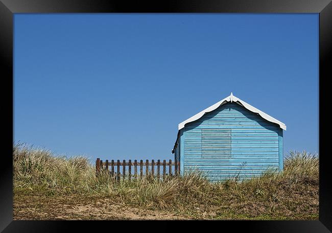 Blue beach hut on a hill Framed Print by John Edwards