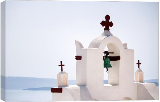 A tower top of a church with cross sign and bells architecture located in oia village in one of Cycladic island in Santorini, Greece against sea. Canvas Print by Arpan Bhatia