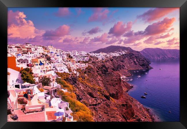 Santorini, Greece: Beautiful city of Oia ( Ia ) on a hill of white houses with blue roof against dramatic pink sky, located in Greek Cyclades islands in Mediterranean sea Framed Print by Arpan Bhatia