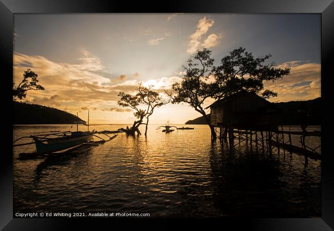 A boat is docked next to the fisherman's home in sunset. Framed Print by Ed Whiting