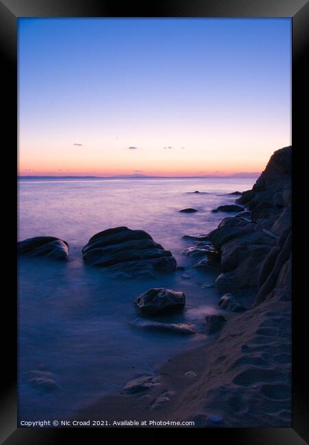 Long exposure of sea around rocks on beach Framed Print by Nic Croad