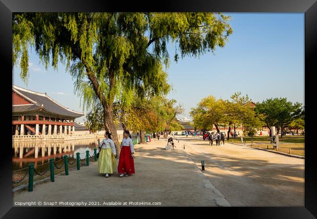 Two women in hanboks walking beside the lake at Gyeongbokgung Palace, Seoul Framed Print by SnapT Photography