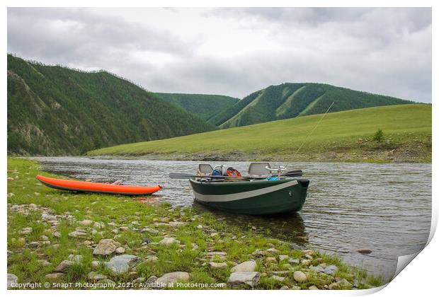 A fishing raft and kayak anchored on grass bank beside the river Print by SnapT Photography