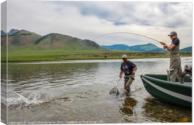 A fisherman with a Taimen Trout on the end of his line in Mongolia, Moron, Mongolia - July 14th 2014 Canvas Print by SnapT Photography