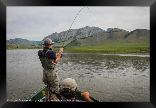 A fisherman with a Taimen Trout on the end of his line in Mongolia, Moron, Mongolia - July 14th 2014 Framed Print by SnapT Photography