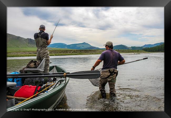 A fisherman with a Taimen Trout on the end of his line in Mongolia, Moron, Mongolia - July 14th 2014 Framed Print by SnapT Photography