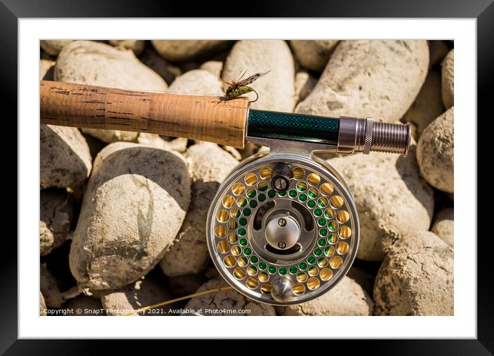 A close up of a trout fly rod, reel and line on rocks, with a cicada fly Framed Mounted Print by SnapT Photography
